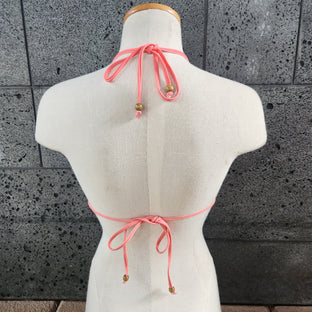 Colorful triangle bikini top on a mannequin against a gray tiled wall.