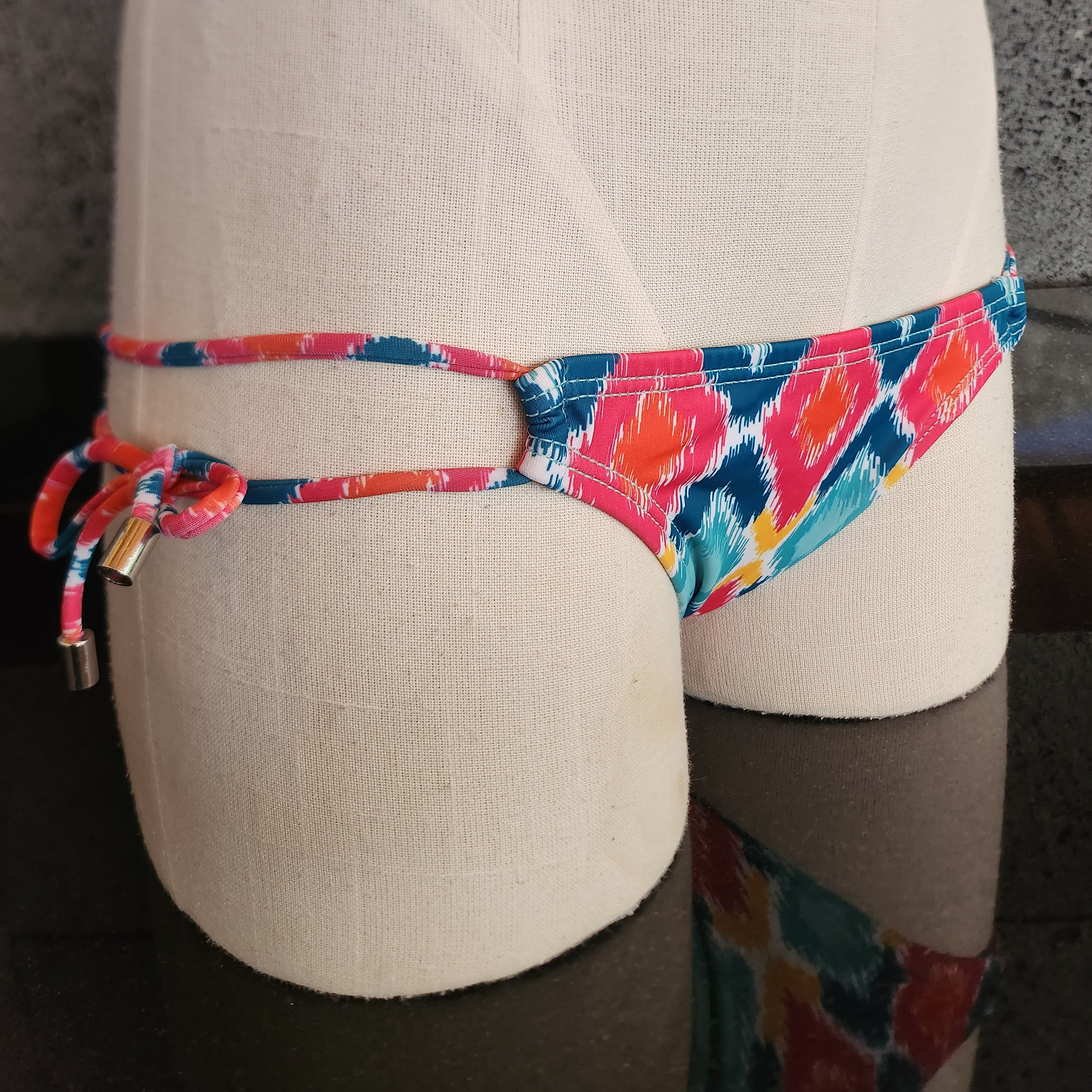 Colorful patterned bikini bottom on a mannequin bust against a neutral background