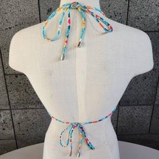 Colorful patterned bikini on a mannequin against a gray tiled floor background