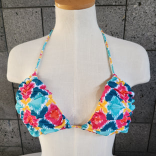 Colorful patterned bikini on a mannequin against a gray tiled floor background