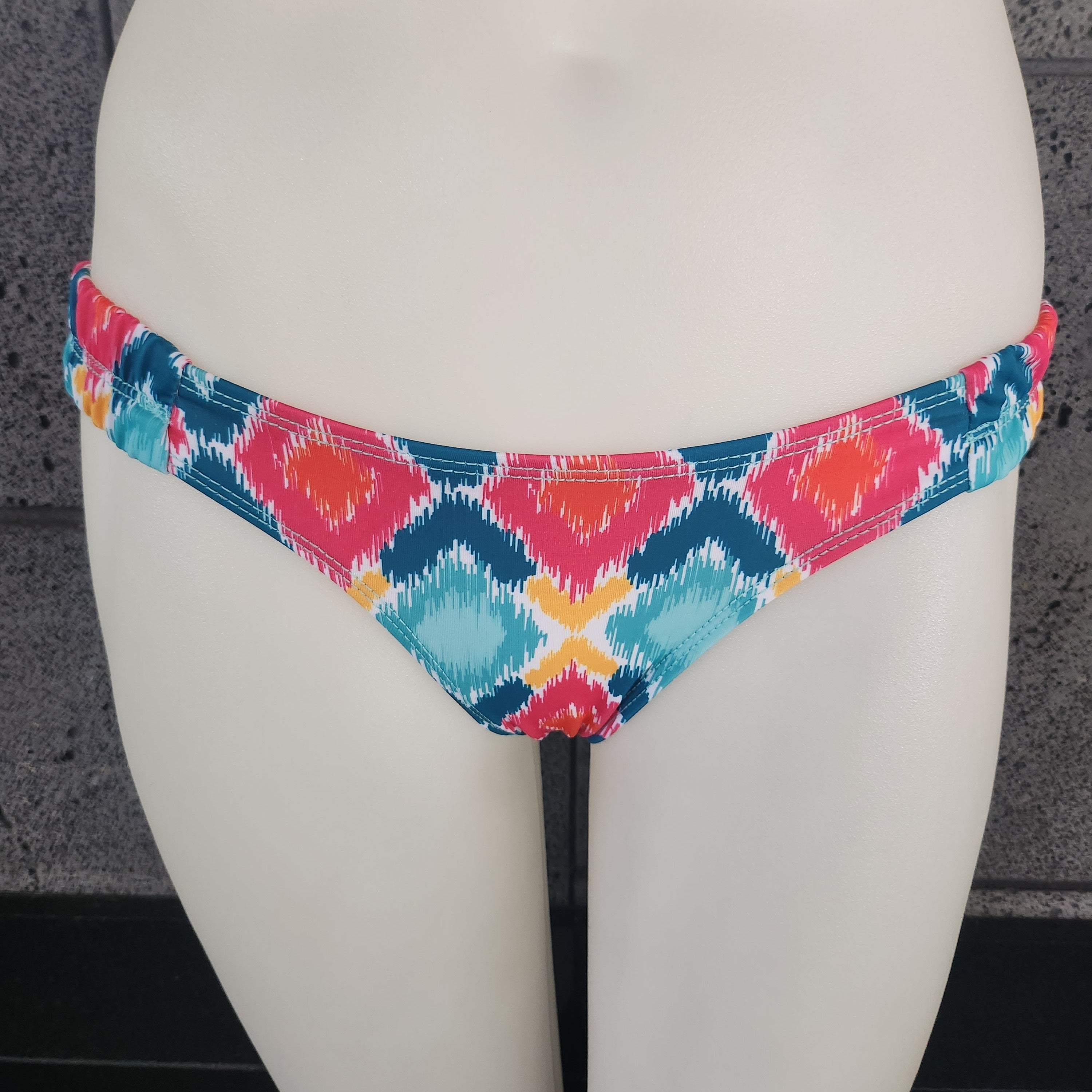 Colorful bikini bottom on a mannequin against a dark background
