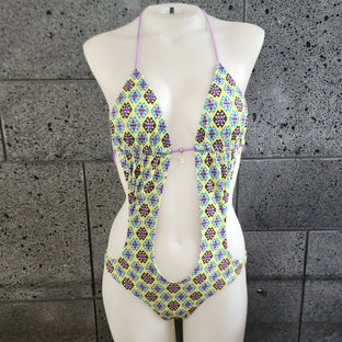 Colorful and geometric patterned monokini on a mannequin against a gray concrete wall.