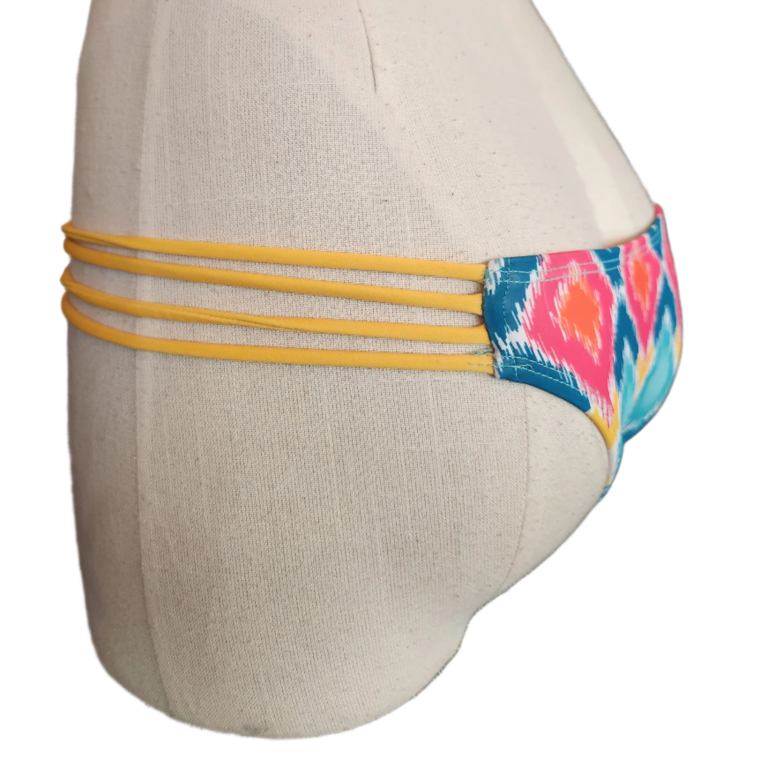 Colorful strappy bikini bottom on a mannequin with a white background