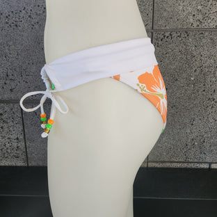 Bikini bottom with blue floral design on a mannequin against a tiled wall.