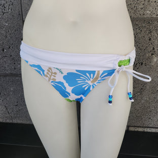 Bikini bottom with blue floral design on a mannequin against a tiled wall.