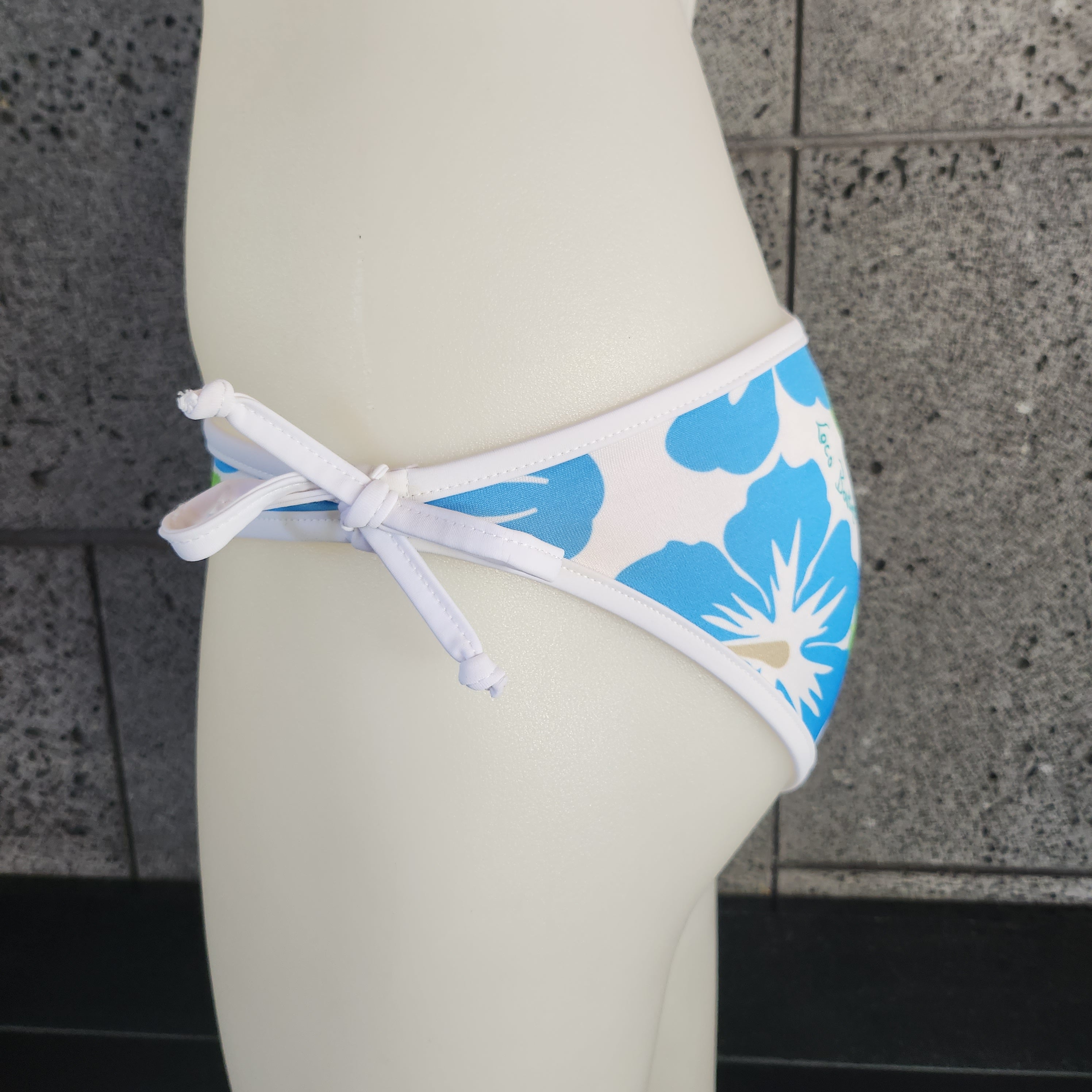 Floral bikini bottom on a mannequin with a textured gray background