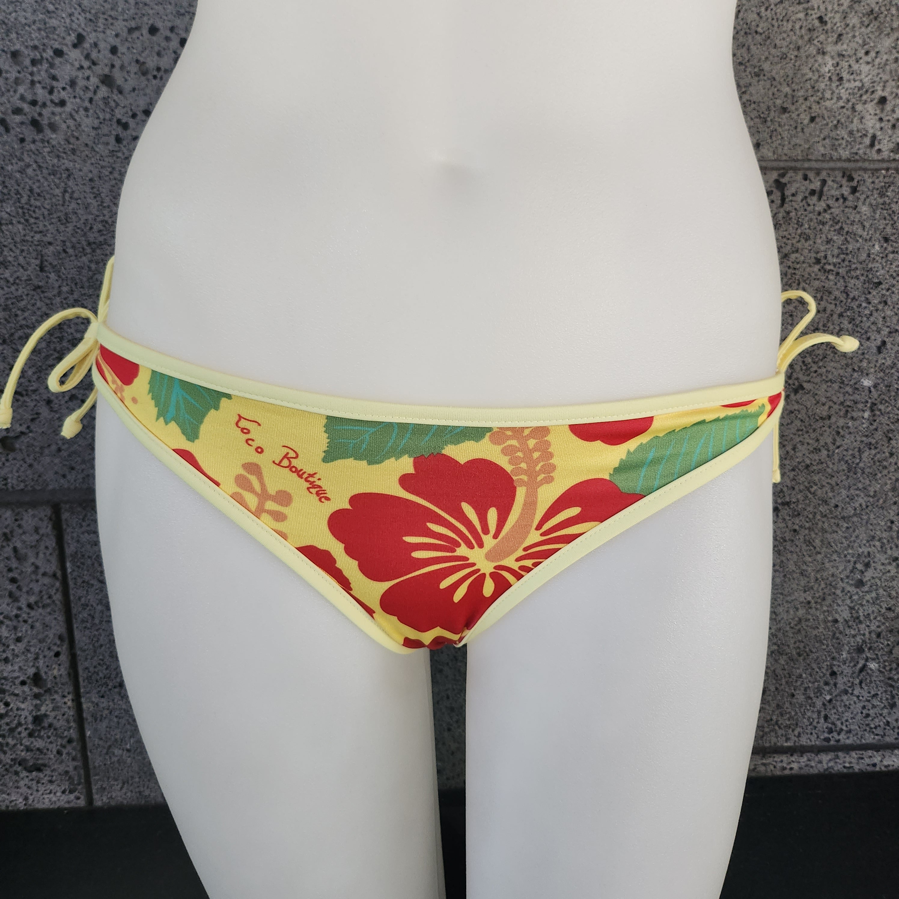 Floral bikini bottom on a mannequin with a textured gray background