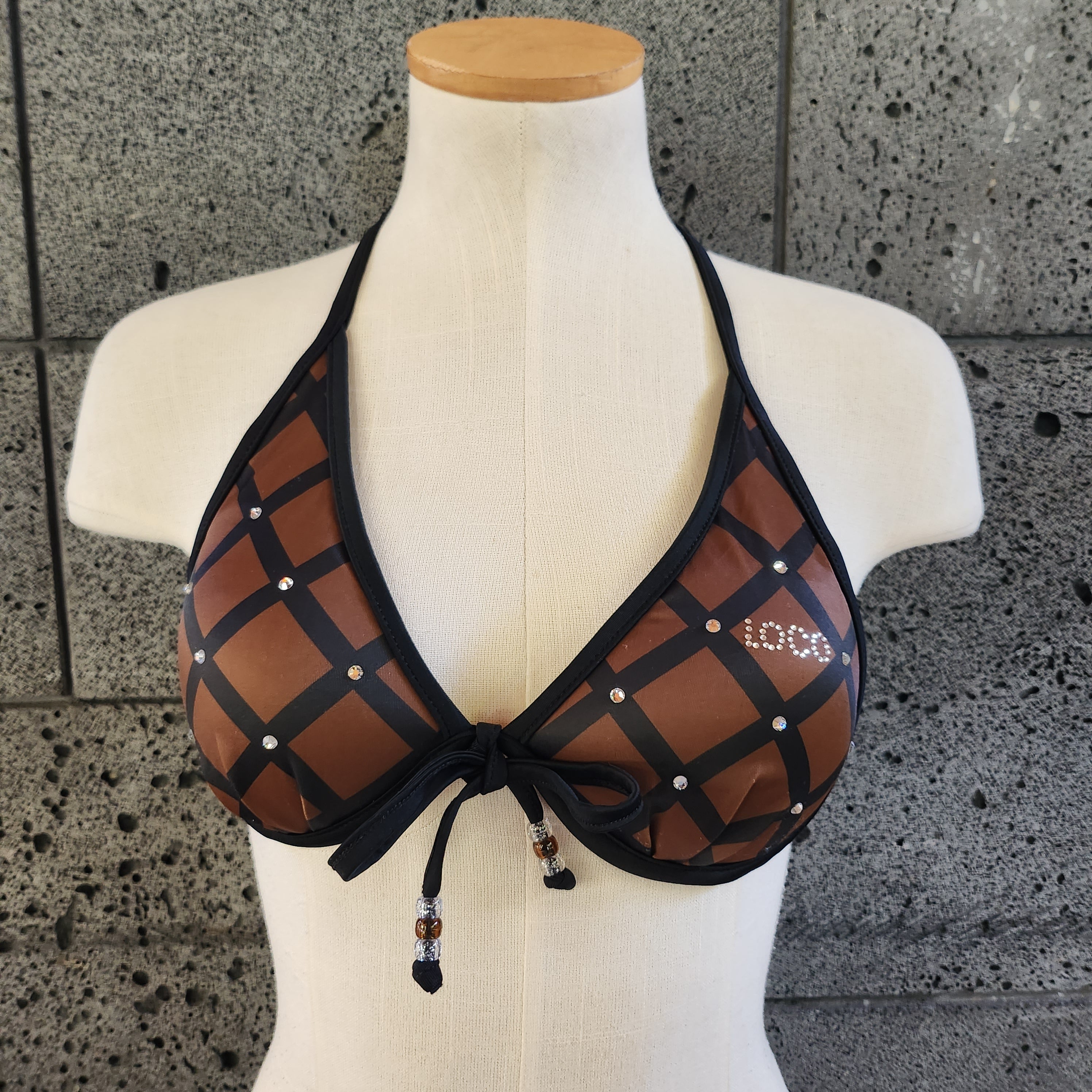 Mannequin wearing a brown bikini top on a textured gray background