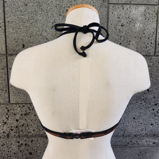 Mannequin wearing a brown bikini top on a textured gray background