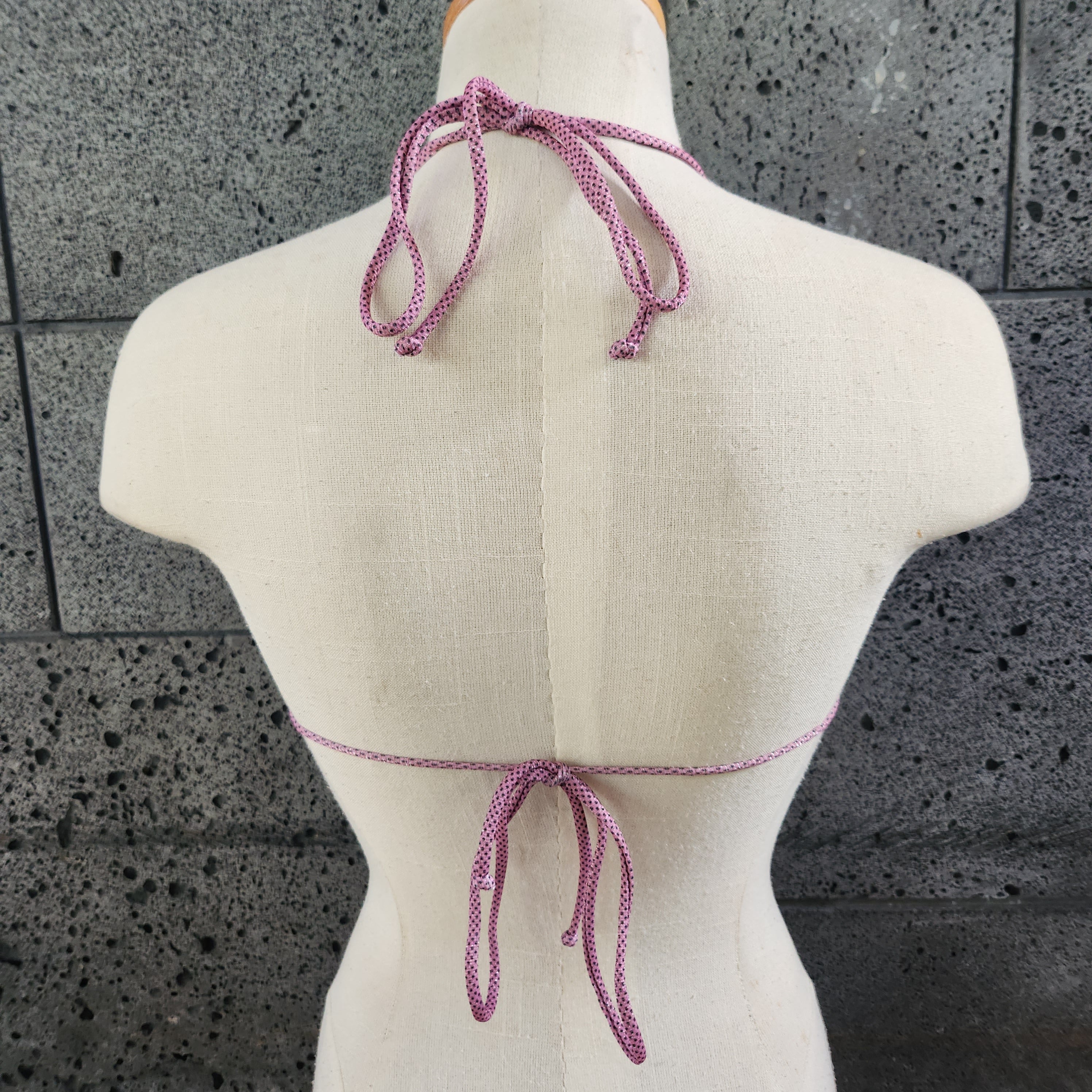 Patterned triangle bikini top on a mannequin against a gray concrete background