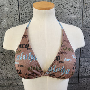 Patterned triangle bikini top on a mannequin against a gray concrete background