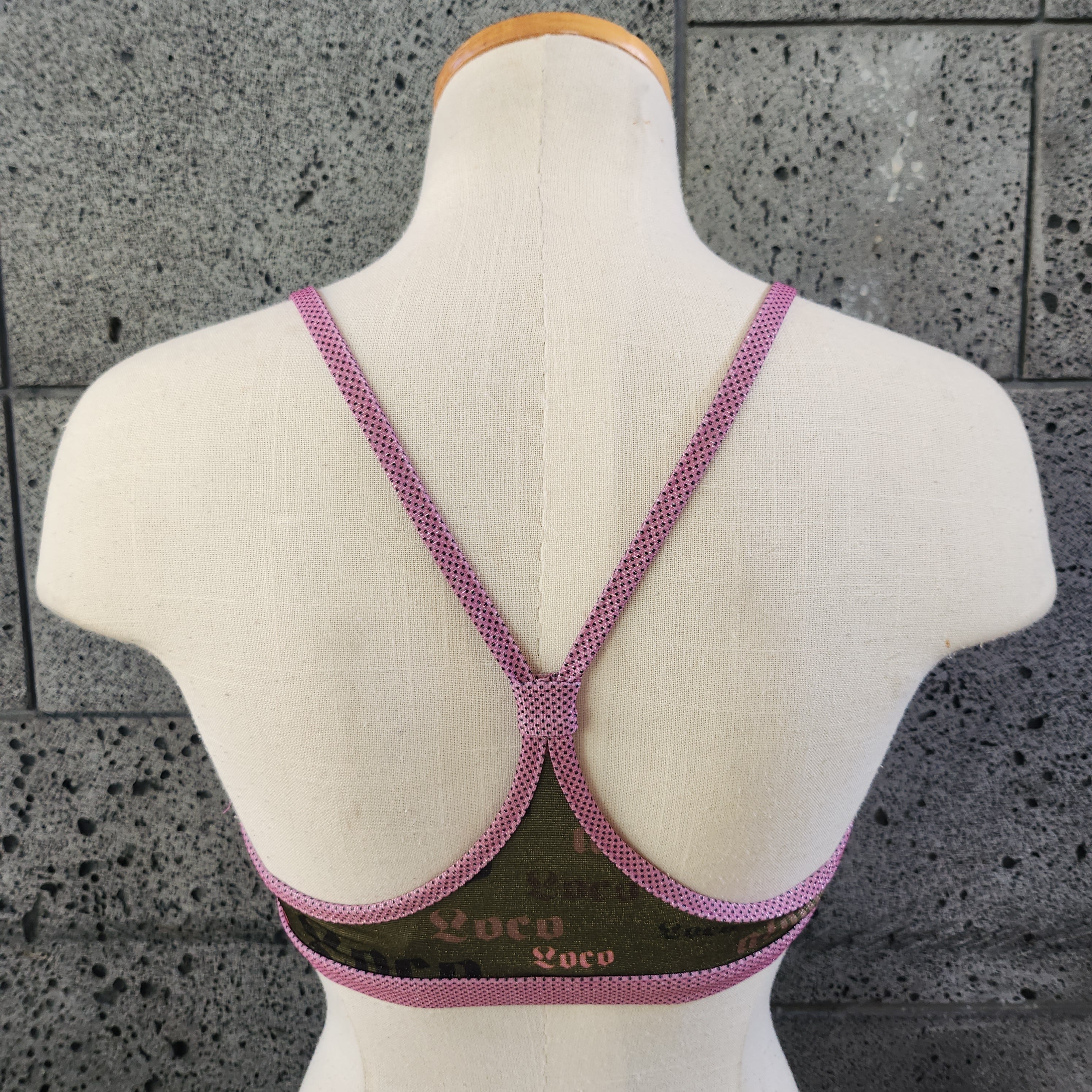Triangle bikini top on a mannequin bust against a gray concrete background