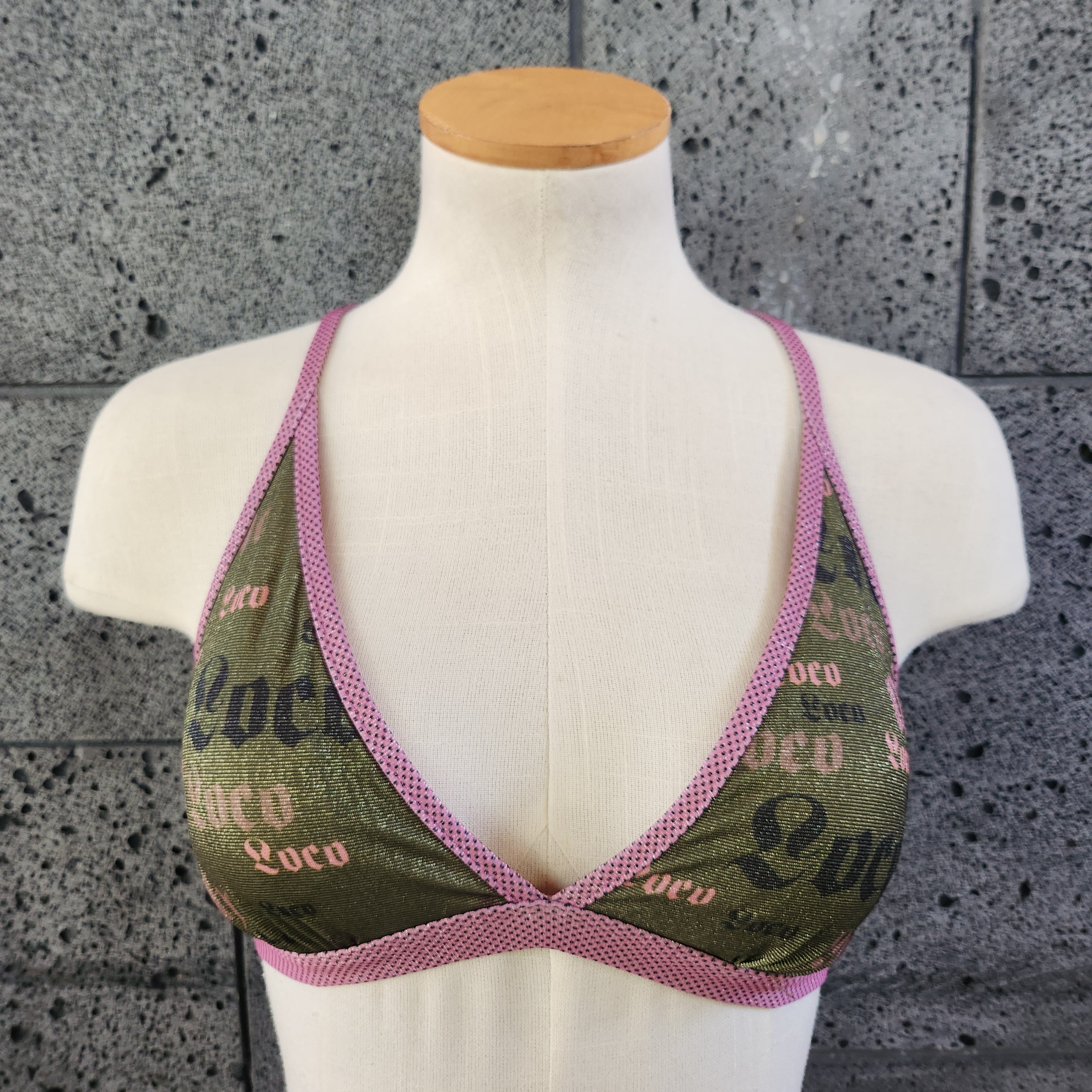 Triangle bikini top on a mannequin bust against a gray concrete background
