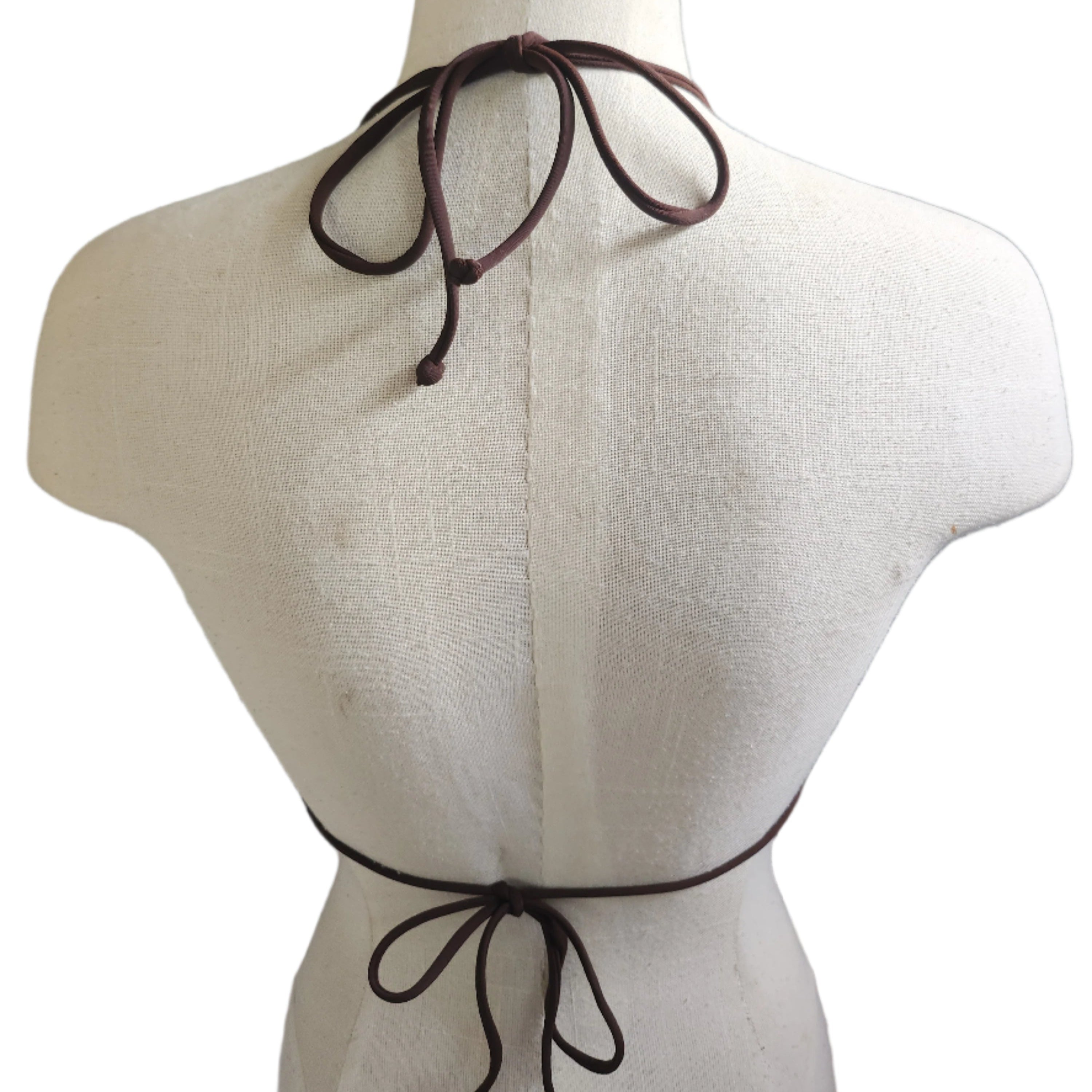 Patterned bikini top on a mannequin against a tiled wall background