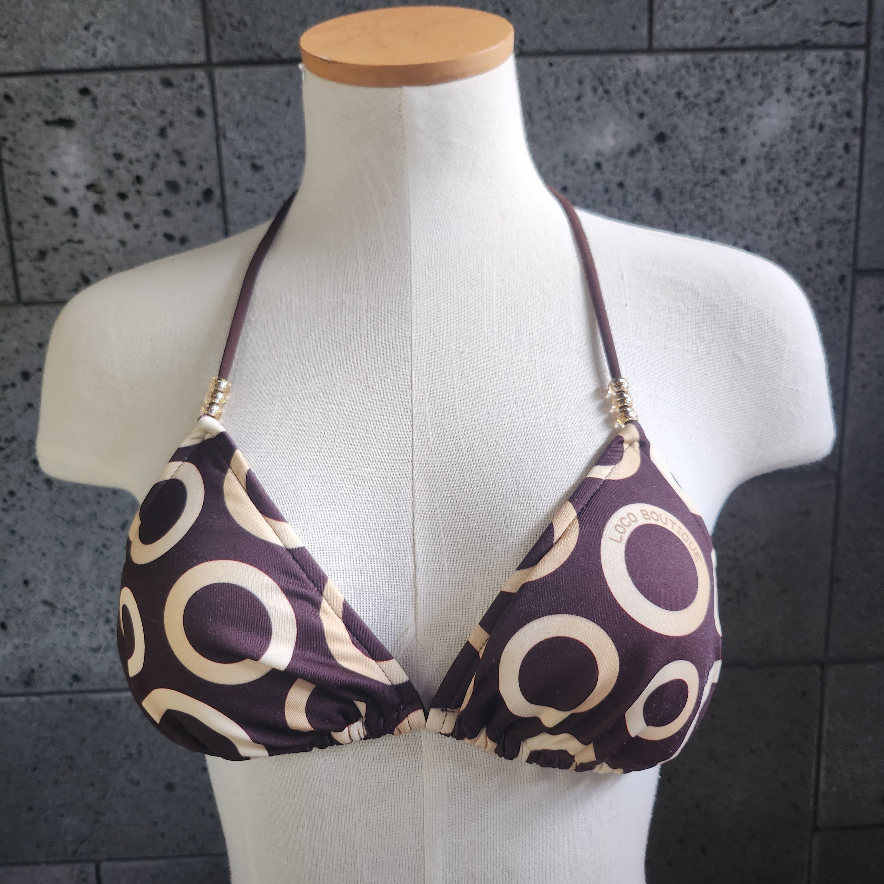 Patterned bikini top on a mannequin against a tiled wall background