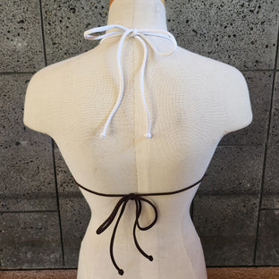 Colorful bikini on a mannequin against a concrete wall.