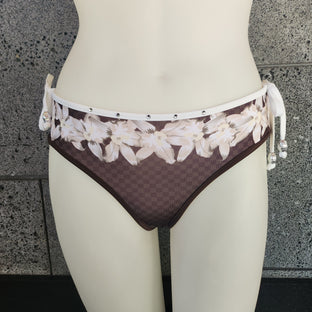 Brown bikini bottom with floral pattern on a mannequin against a gray stone wall.