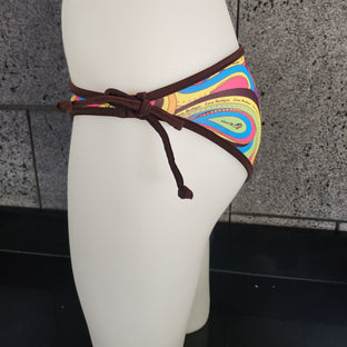 Colorful bikini bottom on a mannequin against a gray wall.