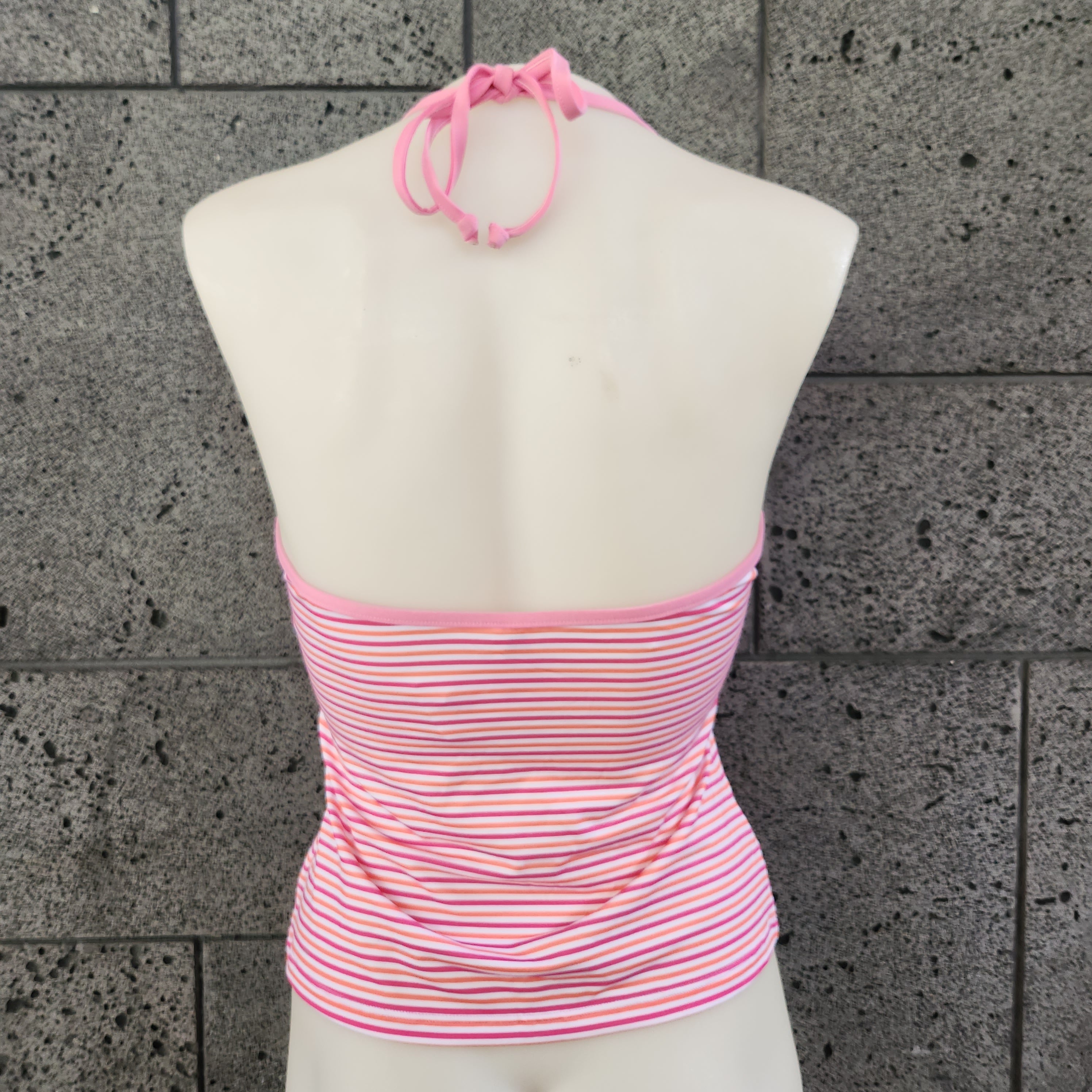 Pink patterned halter tankini top on a mannequin against a gray tiled floor.