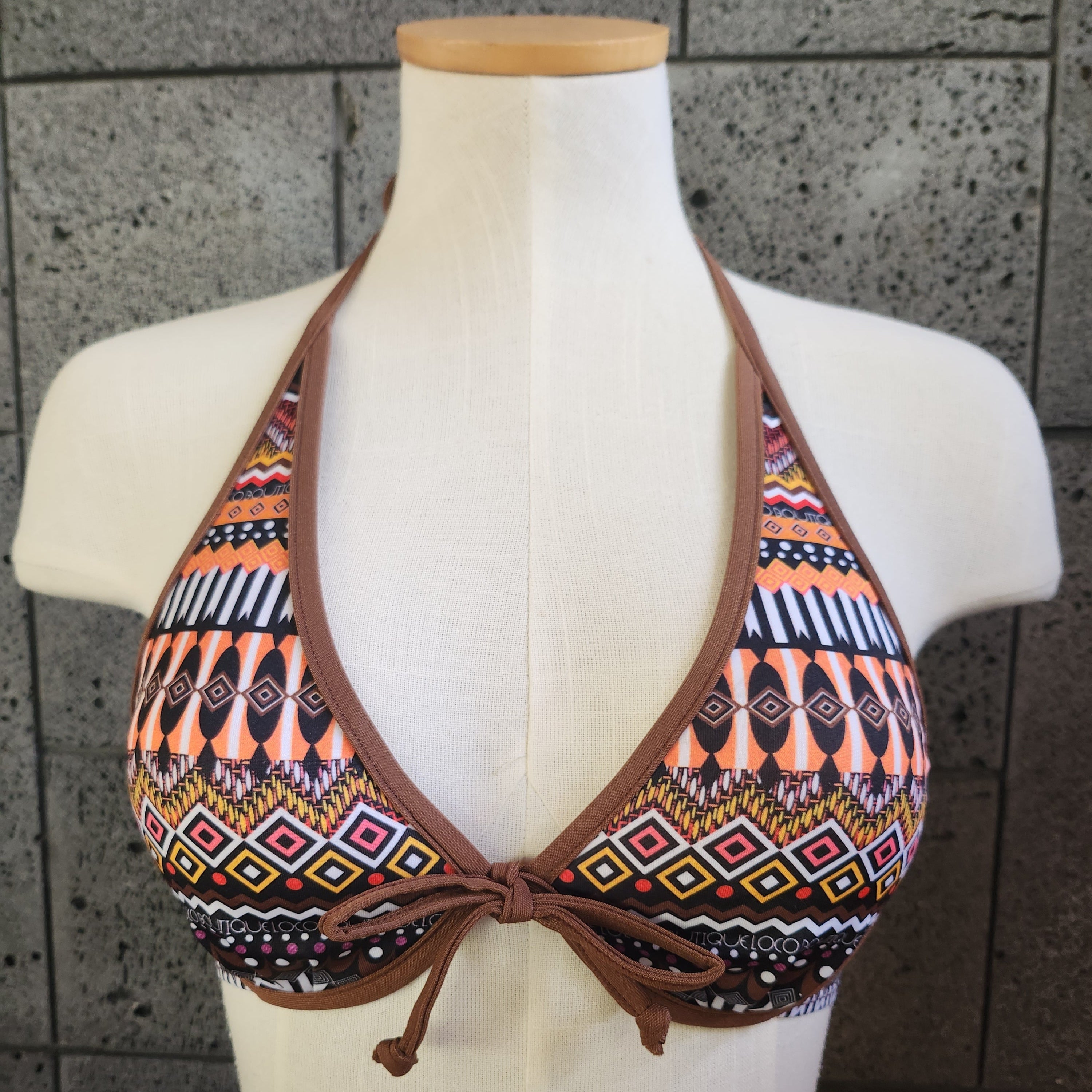 Bikini top with tribal pattern on a mannequin against a tiled background