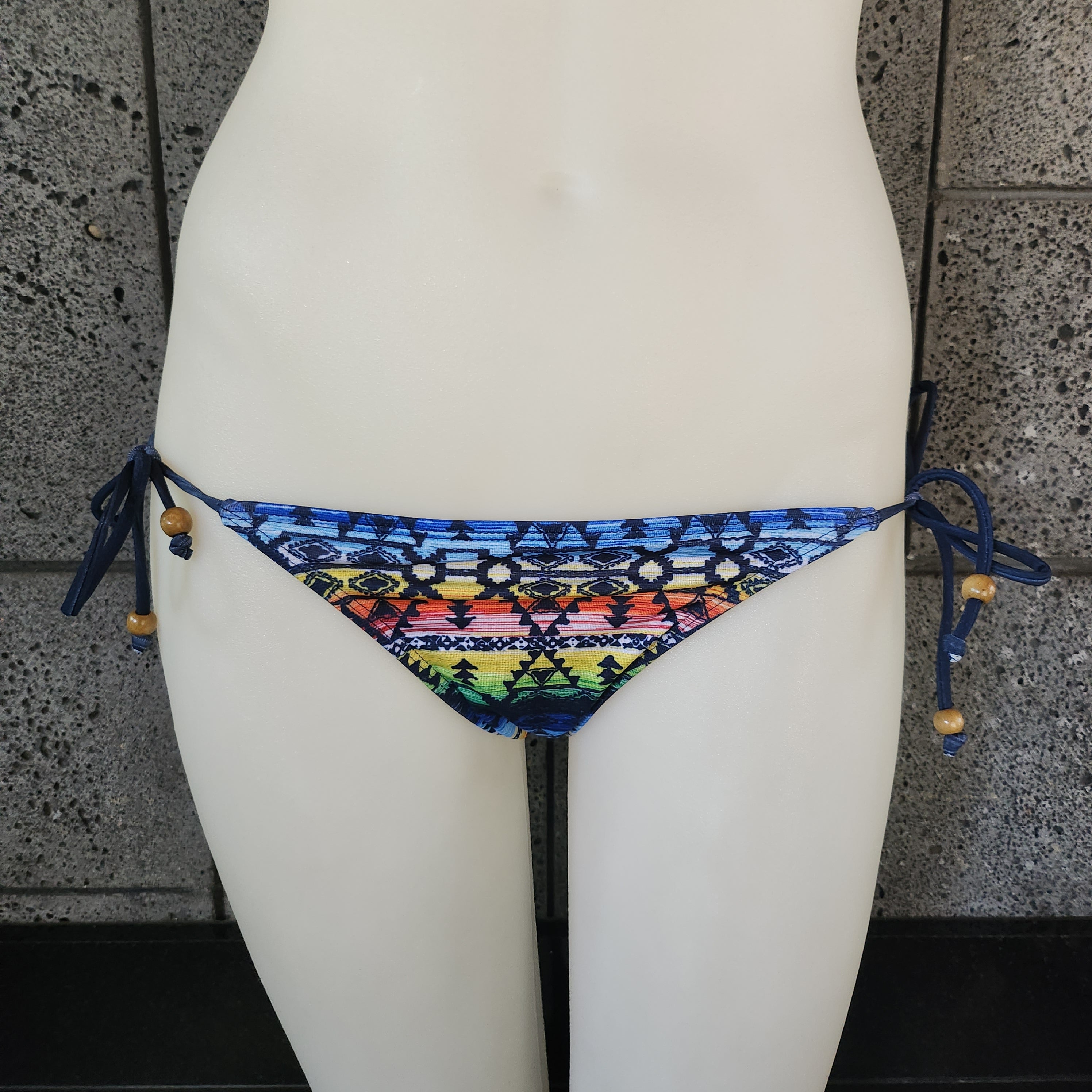 Multicolored patterned bikini bottom on a mannequin against a tiled wall.