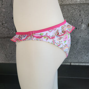 Floral-patterned bikini bottom on a mannequin against a concrete wall.