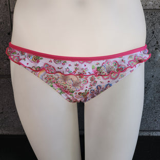 Floral-patterned bikini bottom on a mannequin against a concrete wall.