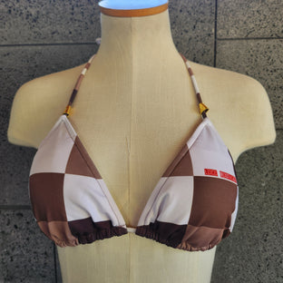 Brown and white checkered bikini top on a mannequin against a tiled wall.