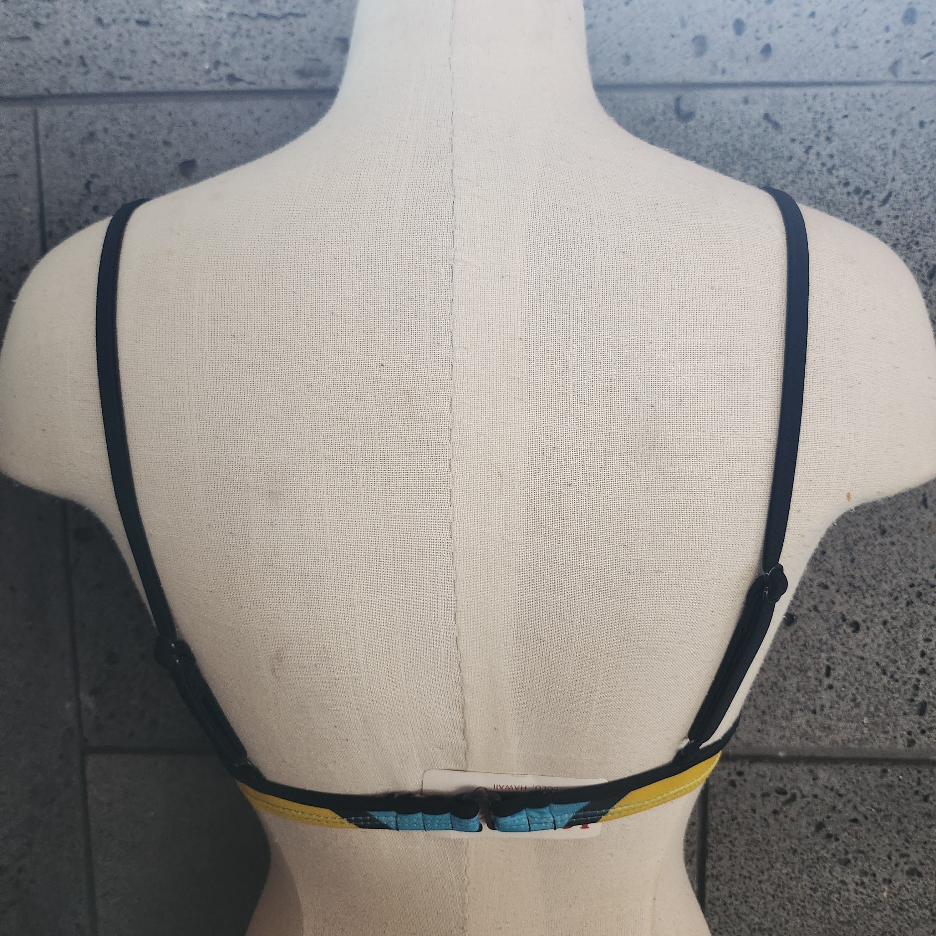 Colorful bikini top on a mannequin against a gray background