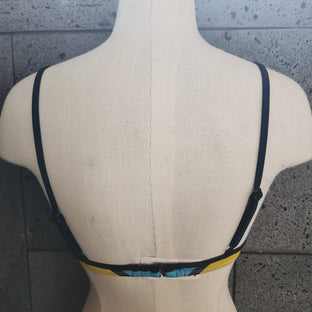 Colorful bikini top on a mannequin against a gray background