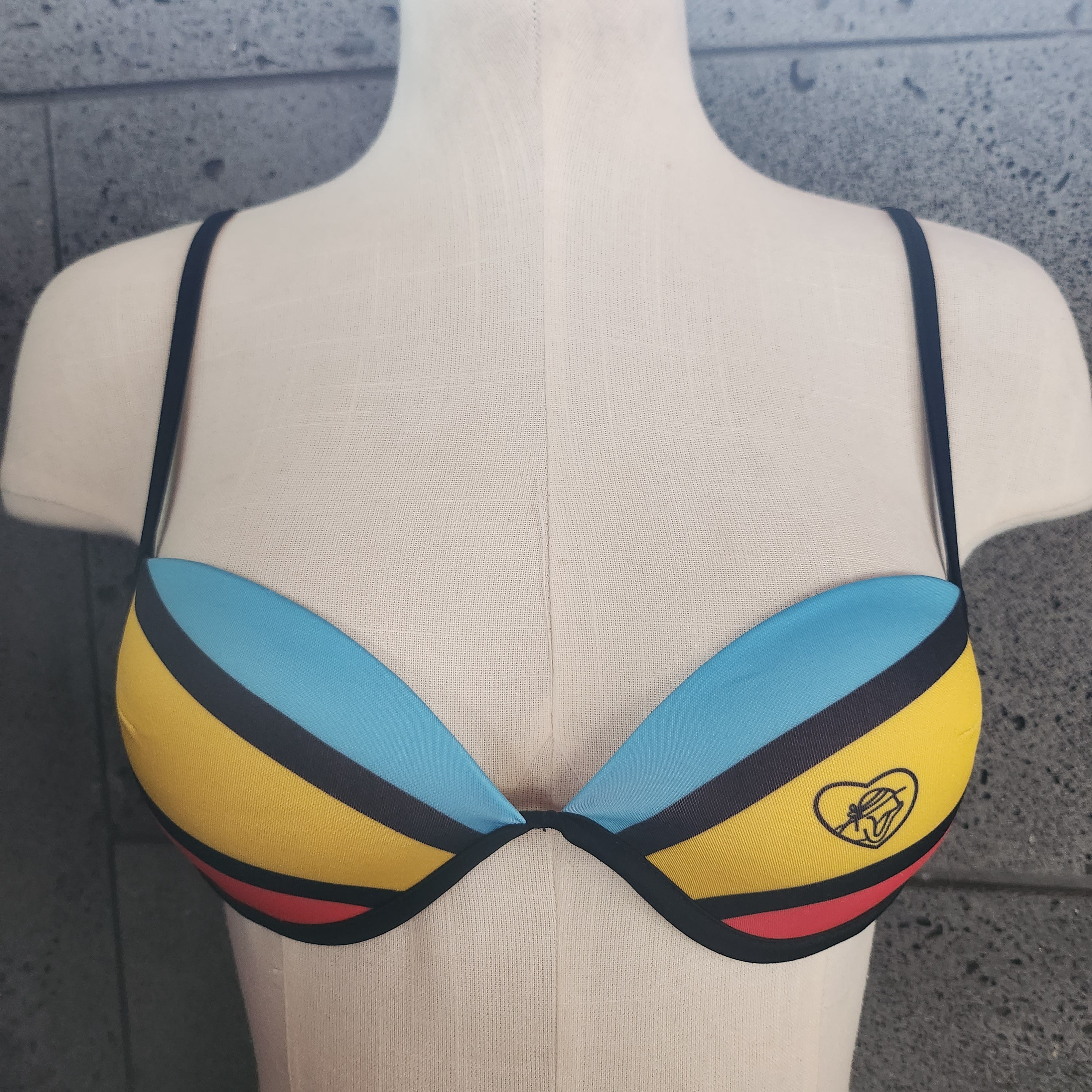 Colorful bikini top on a mannequin against a gray background