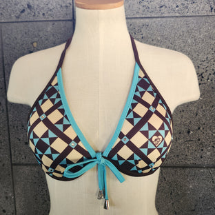 Geometric patterned bikini top on a mannequin against a tiled wall.