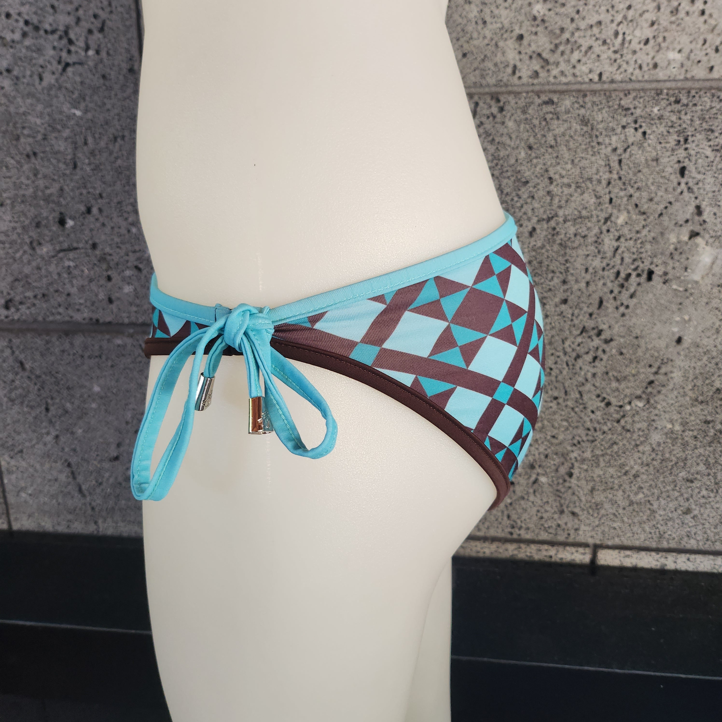 Bikini bottom with geometric pattern and blue straps on a white surface.