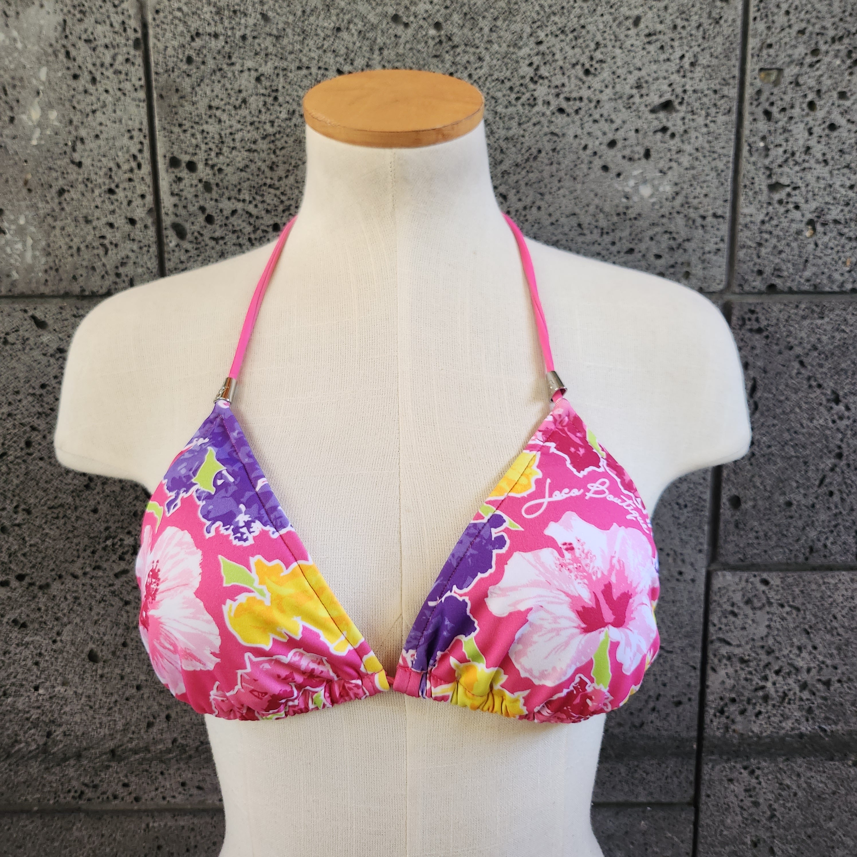 Floral triangle bikini top on a mannequin against a gray tiled background.