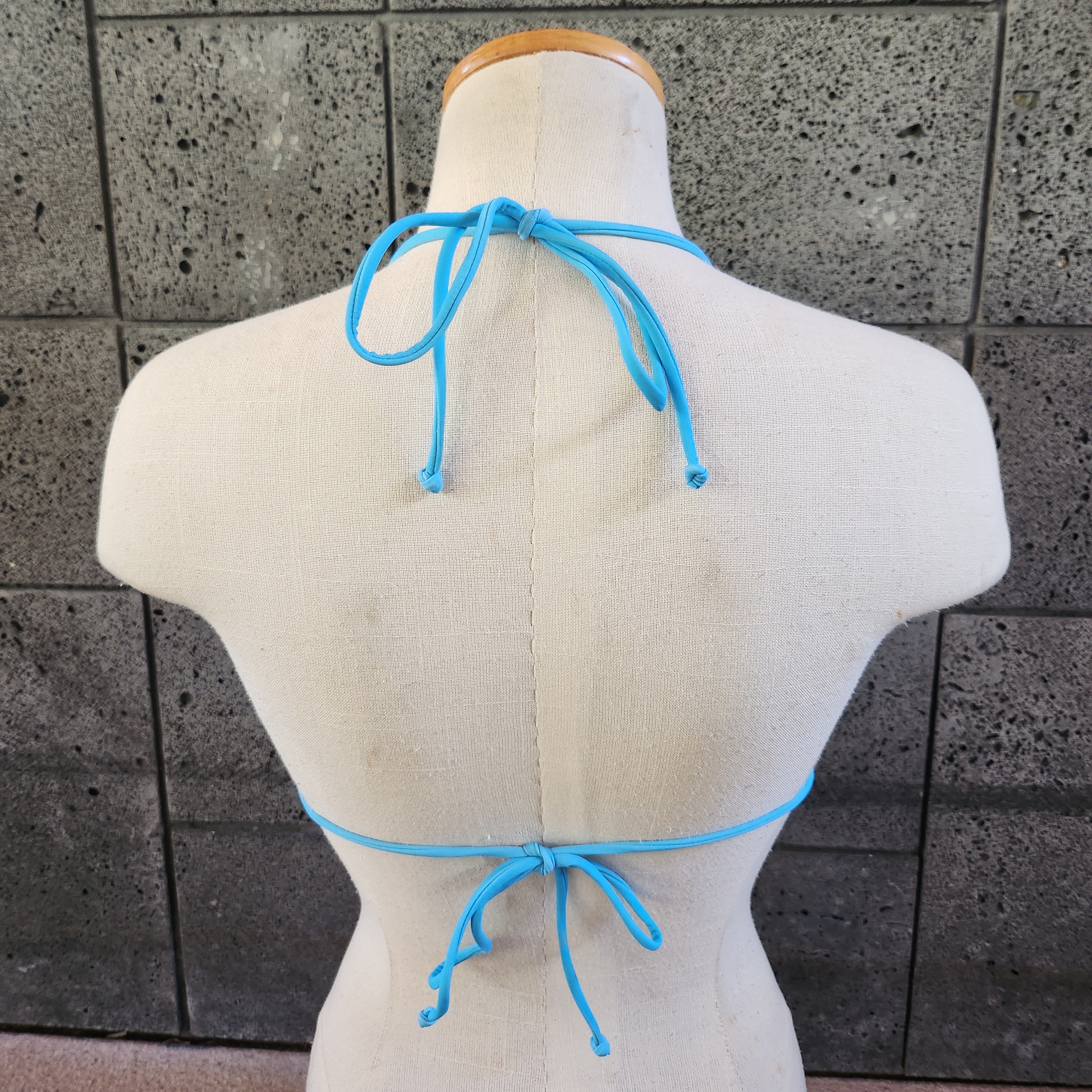 Floral triangle bikini top on a mannequin against a gray tiled background.