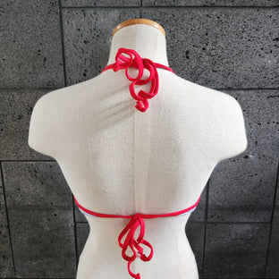 Colorful underwire top on a mannequin against a textured wall.