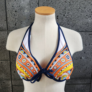 Colorful underwire top on a mannequin against a textured wall.