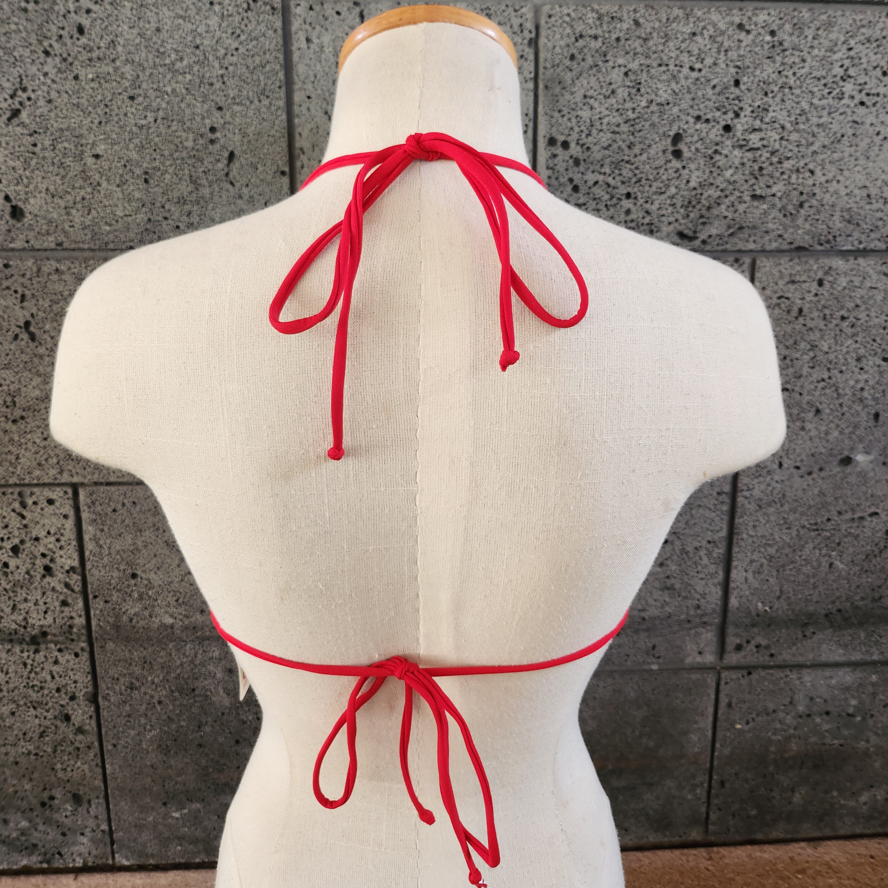 Colorful triangle top on a mannequin against a concrete wall.