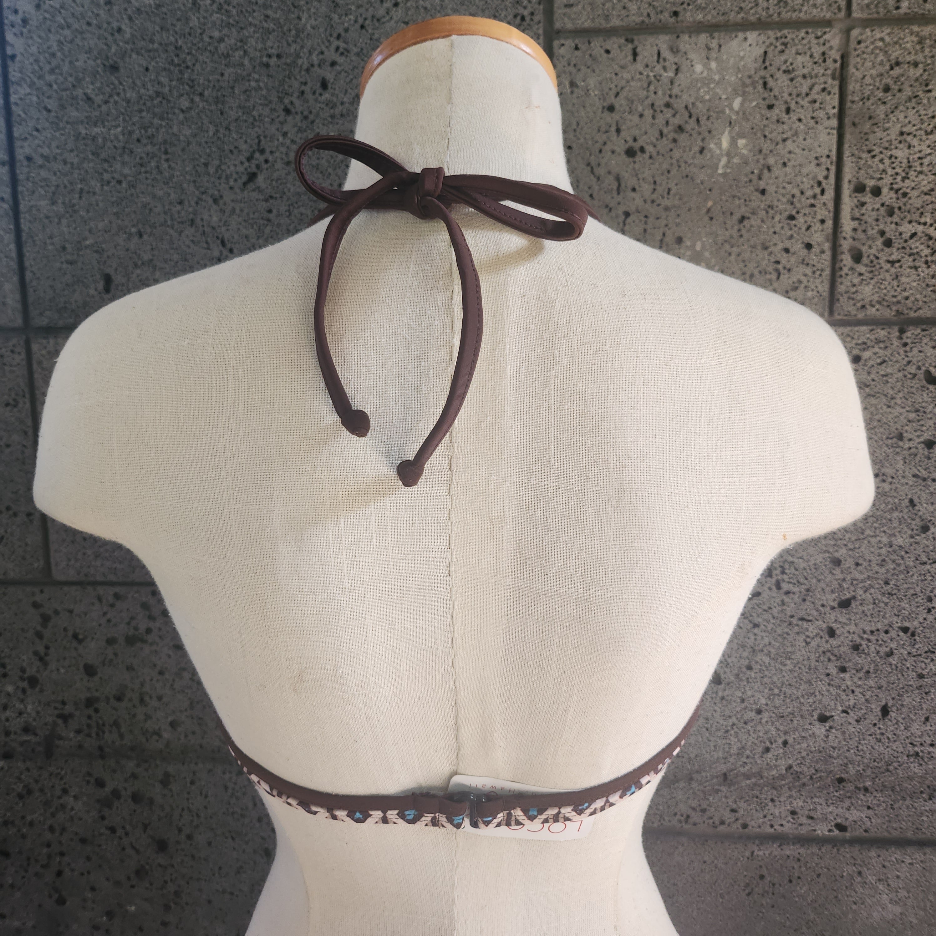 Navy blue bikini top on a mannequin against a gray tiled wall.