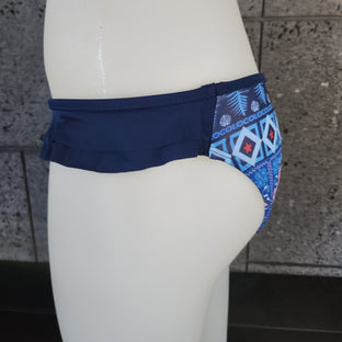 Brown bikini bottom with geometric pattern on a mannequin against a gray wall.