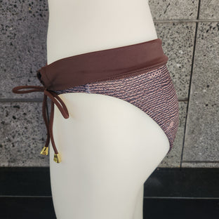 This image captures the essence of the Loco Boutique Burlap Folded Over bottom, a chic and stylish piece of swimwear designed with a distinctive burlap-inspired texture. The model is shown wearing the white bikini bottom, which features a trendy folded-over waistband that allows for adjustable fit.
