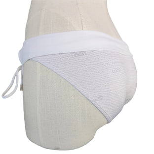 This image captures the essence of the Loco Boutique Burlap Folded Over bottom, a chic and stylish piece of swimwear designed with a distinctive burlap-inspired texture. The model is shown wearing the white bikini bottom, which features a trendy folded-over waistband that allows for adjustable fit.