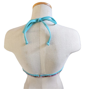 A woman wearing a turquoise and multicolor floral underwire bikini top with a bow front and back hook closure.