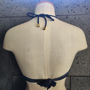 Bikini top with chain pattern on a mannequin against a textured wall.