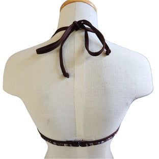 Brown patterned bikini top on a mannequin against a tiled wall.