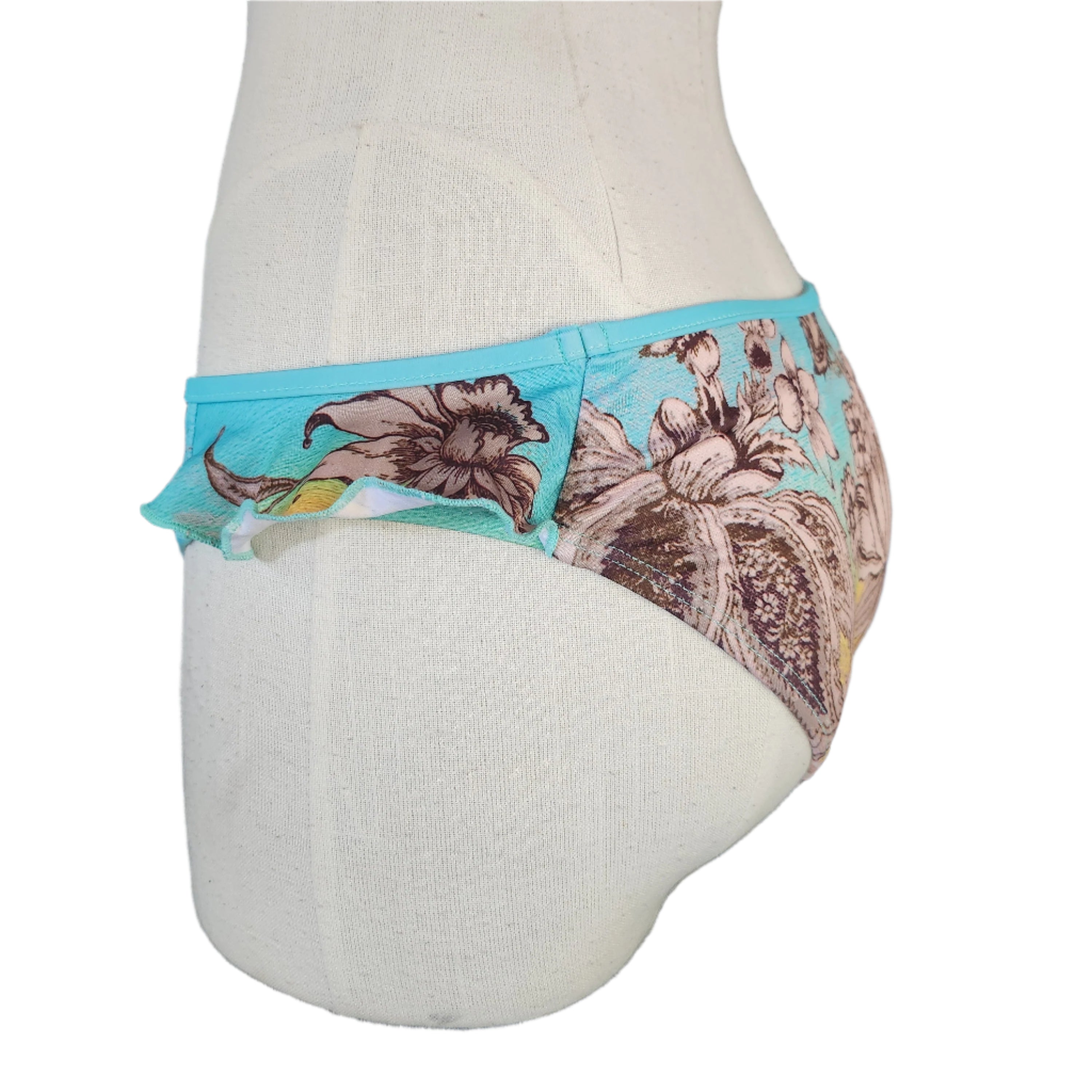 A close-up image of a person wearing a multicolor floral-patterned bikini bottom with side ruffles.