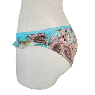 A close-up image of a person wearing a multicolor floral-patterned bikini bottom with side ruffles.