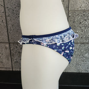 Navy floral bikini bottom on a mannequin against a tiled wall.