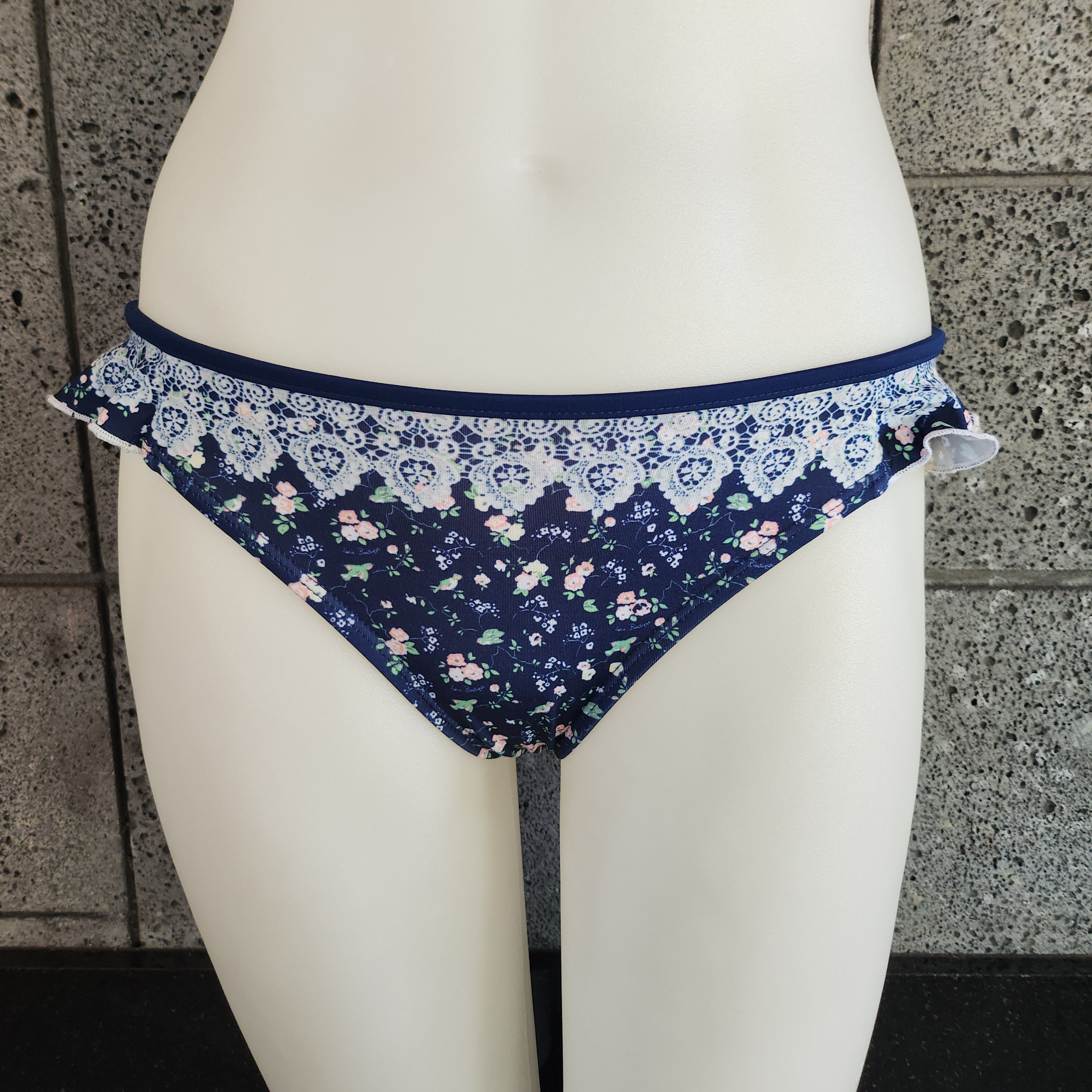 Navy floral bikini bottom on a mannequin against a stone wall background