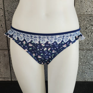 Navy floral bikini bottom on a mannequin against a stone wall background